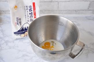 先将液体类的食材放在盆中。然后加入炼乳、糖，混合一下。请注意，盐和黄油不要放入！液体的量可以微调，牛奶一般预留出10-15克来，以便随时调整面团的软硬度。不必刻意鸡蛋是55克还是50克，鸡蛋不够，牛奶来凑，它与牛奶的加起来的量就行。