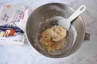 然后放入吐司粉和酵母。然后与盆中的液体混合。记住，盐和黄油还是不要加入！拌匀后，我们可以根据情况决定预留出来的牛奶是加还是不加或者少量加入。