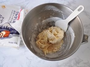 然后放入吐司粉和酵母。然后与盆中的液体混合。记住，盐和黄油还是不要加入！拌匀后，我们可以根据情况决定预留出来的牛奶是加还是不加或者少量加入。