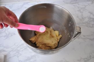 将面盆放到厨师机上，先用厨师机低速搅打，让它成团，然后开三档的速度打至面团能拉出厚膜，这时再加入黄油和盐。