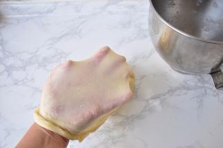 待黄油被面团全部吸收，将厨师机调成高速运转，约5分钟后可测试面团薄膜，如果能拉出均匀大片薄膜，能套在手上有弹性不易被撑破，如果撑破后破洞是光滑圆形，撕拉开后面面能直线裂开，这个面团就可以了。