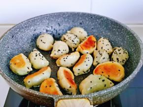 待水分烧干后，撒上熟黑芝麻关火，端起锅摇晃均匀，使芝麻均匀粘在煎饺上