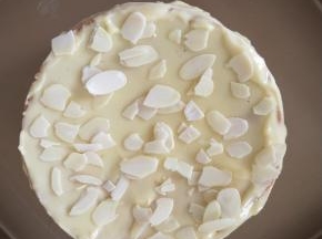 12、取出蛋糕放在烤盘上，将奶酪糊涂在蛋糕表面（撒杏仁片）和四周，再送入烤箱，只开上火200-230度，烘烤5分钟，表面上色即可