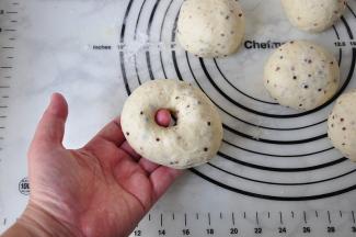 将面团用手从中间掏一下洞，一定要从中间掏。然后边转边将洞口扩大，并随时调整形态，保持它的圆形状态。