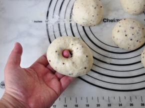 将面团用手从中间掏一下洞，一定要从中间掏。然后边转边将洞口扩大，并随时调整形态，保持它的圆形状态。