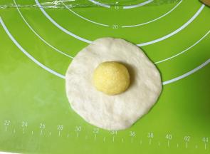 取一个松驰好的面团压扁擀成圆形，放入一个椰蓉馅球。