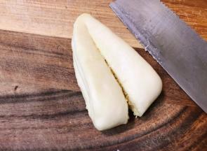 将其移至菜板上，用刀如图示在尖部留一点距离将其等份切开。