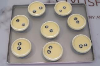 一个蛋挞放入两粒冷冻的蓝莓。