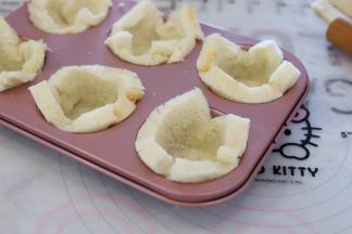 准备一个6连的圆形杯子蛋糕模，吐司片放好，边缘压贴实。