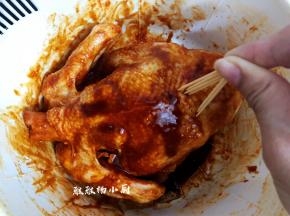 接着就重要步骤来了，用牙签或是叉子在鸡身上戳出小洞，这样能更有效的吸收，能使整只更入味，戳好之后，可以给整只鸡做个按摩，鸡肚子也用酱调和姜片给涂抹一遍