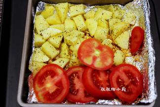把烤好的鸡肉取出，将土豆倒入烤箱中，再把番茄切成片