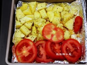 把烤好的鸡肉取出，将土豆倒入烤箱中，再把番茄切成片