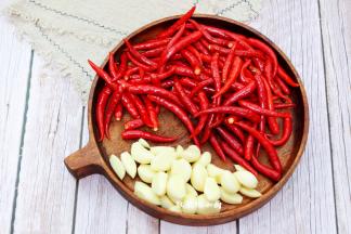 把擦干水分的蒜头和辣椒，用一个大点的盘子装着，再次放在通风处风干水分