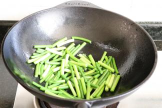 将铸铁锅清洗干净后重复步骤4、5，倒入蒜苔大火快速翻炒；
