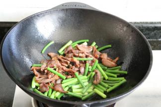 蒜苔炒软后倒入鸭肫片一起翻炒；
