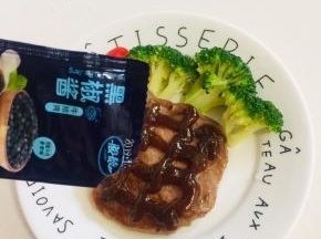 在牛排上挤上黑胡椒调料汁儿。