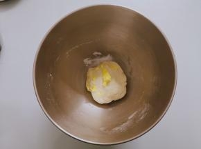 面团揉到稍微光滑放入软化好的黄油，低速揉匀，加盐转高速