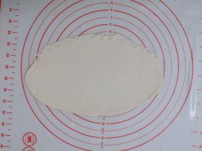 醒好的面团拿出来，用手拍打面团，排气；然后用擀面杖，把面团擀成比较薄牛舌状