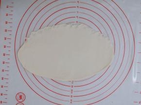 醒好的面团拿出来，用手拍打面团，排气；然后用擀面杖，把面团擀成比较薄牛舌状