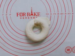 然后圈起来，将另一头放在压扁的面团上。包好，然后捏紧收口处。一定要捏紧