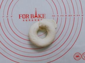 然后圈起来，将另一头放在压扁的面团上。包好，然后捏紧收口处。一定要捏紧