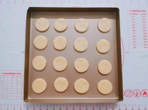 用刮板小心翼翼地将圆形挑起放入烤盘中。边角料可以继续揉合在一起，再擀开使用