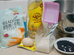 如图这款我们先来制作餐包，用料金龙鱼面包粉500克，牛奶400克，鸡蛋1个，白糖60克，玉米油50克，熟芝麻1碟，酵母4克，细盐5克