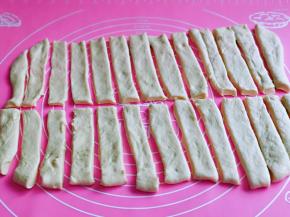 醒发好的面团，用擀面杖擀成薄饼状，再用切刀切出等份的小长条，再每条长条的中间再切一刀，如图。