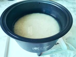 首先把米浸泡一会，倒入甑子中沥干，取电饭煲内胆倒入清水，把甑子装入内胆中。