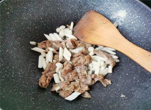 把白玉菇洗净，切小段，倒入锅中跟肥牛一起翻炒变软。
