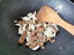 把白玉菇洗净，切小段，倒入锅中跟肥牛一起翻炒变软。