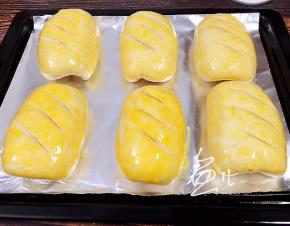 发酵约30分钟后，在面包坯表面割几刀，刷蛋液