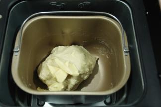 此时可以加入软化好的黄油，继续打面。直到程序差不多结束，可以取一点面团拉开观察一下，能拉出比较完整且略薄的膜，小餐包不像吐司，吐司需要手套膜，小餐包没有这么高要求。