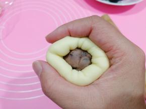 将面皮往馅料球上贴，然后右手虎口往上收拢。