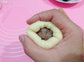 将面皮往馅料球上贴，然后右手虎口往上收拢。