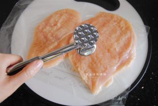 接下来是处理鸡胸肉的最关键一步，用松肉锤把鸡肉做个马杀鸡，轻轻的全部敲个遍，让鸡肉的肉质变得松软，这是鸡肉吃起来不会柴的关键，值得注意的是，松肉的时候要上下垫一张爆香膜，不然就全粘在锤子上了。
