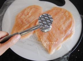 接下来是处理鸡胸肉的最关键一步，用松肉锤把鸡肉做个马杀鸡，轻轻的全部敲个遍，让鸡肉的肉质变得松软，这是鸡肉吃起来不会柴的关键，值得注意的是，松肉的时候要上下垫一张爆香膜，不然就全粘在锤子上了。