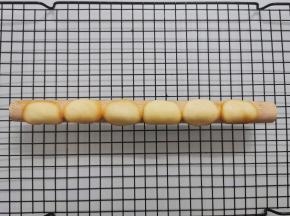 取出烤盘，趁热将烤好的薄饼铲起，放在圆形的小擀面杖（或其他细长的棍状工具）上，使它弯曲。等面糊冷却后会定型，变脆。 也可以直接用手将薄饼弯曲的。但如果你怕烫，还是带上隔热手套操作比较好。 烤好的薄饼要趁热立刻弯曲。冷却以后会变脆，就弯折不了了