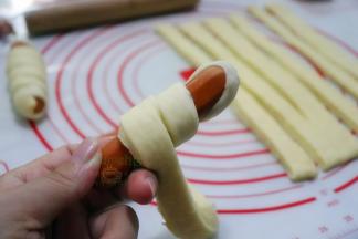 取脆皮肠出来，用面皮卷着脆皮肠，不规则卷，裹的像木乃伊一样，其中眼睛的部位不需要裹面皮。