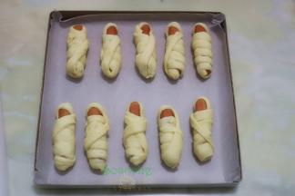 烤盘垫上硅油纸，均匀放入做的木乃伊面包胚，放入烤箱发酵，时间45分钟，烤箱底部放一盘温水。