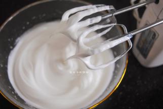 接下来处理蛋白，将细砂糖分3次加入蛋白里，用电动打蛋器高速搅打，第3次加入细砂糖搅打的时候，要低速慢打，不要打过头了，最后的状态是出现小尖角就是打好了。