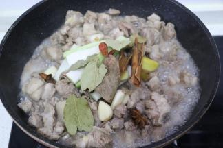 倒入羊肉翻炒，变色出油后，加入葱姜蒜八角桂皮香叶干辣椒翻炒。