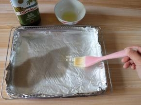 在烤箱配套的炸篮里铺一层锡箔纸，刷上一层橄榄油；