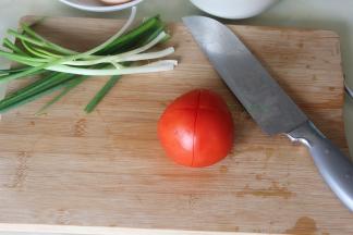 香葱洗净，切葱花。西红柿外皮用盐搓洗，然后用水冲洗干净，用刀在西红柿的划十字。划十字是为了去皮容易。