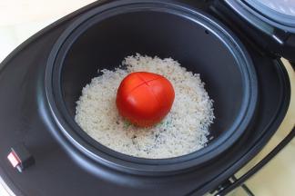 电饭锅倒入适量的水，把洗净的大米放入甑子，大米上面放西红柿，划开的面朝上。大米和水的比例，1杯大米9杯水。