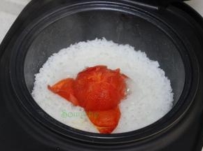 饭煮熟之后，自动跳到保温状态，这个时候开盖，把西红柿的外皮去掉，用筷子把西红柿拌均。