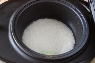 把洗净的大米倒入电饭锅里，加适量的水，每个锅不同、大米不同，水的比例略有差异。1杯米9杯水，2杯米10杯水，每加一杯米就增加1杯水，以此类推。