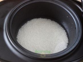 把洗净的大米倒入电饭锅里，加适量的水，每个锅不同、大米不同，水的比例略有差异。1杯米9杯水，2杯米10杯水，每加一杯米就增加1杯水，以此类推。