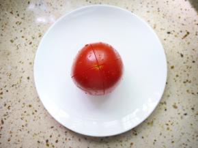 番茄洗干净，用刀在番茄上划一个十字。