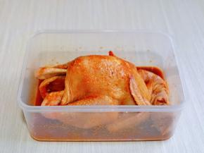 再次按摩鸡身体部位，使整只鸡完成吸收到酱料汁，放入保鲜盒中，盖上盖子，放冰箱腌制12小时以上，途中可以取出来再次按摩一次，这样会更入味。